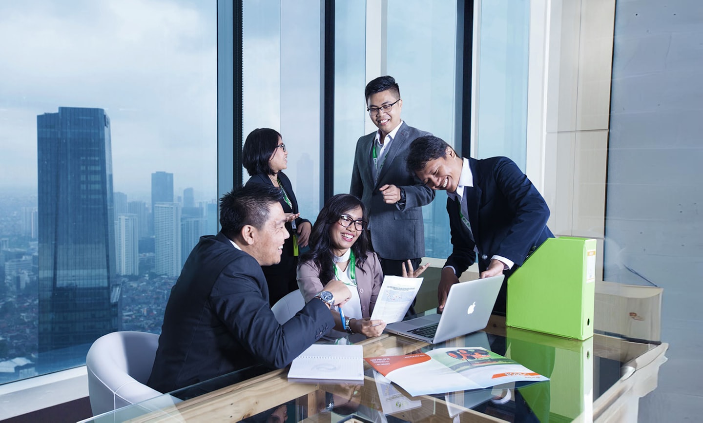 Business professionals collaborate around a conference table in a modern office.