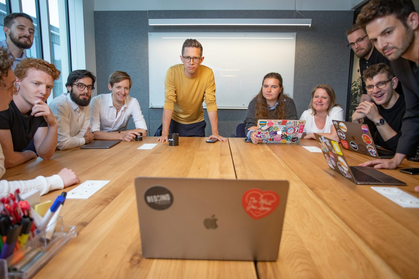 Professionals collaborate around a wooden table in a modern office.